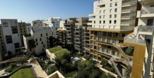 Paysage résidentiel urbain avec des immeubles d'appartements modernes aux designs variés. Jardins sur les toits et végétation luxuriante créent une atmosphère dynamique et respectueuse de l'environnement.